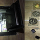On the left is a floor safe with stacked money in cellophane wrappers, and on the right is several gold bitcoins in plastic wrappings.